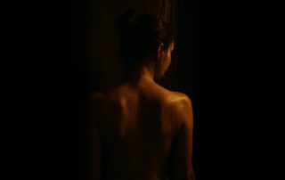 woman’s naked back in the shower