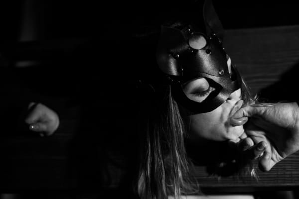 Schwarz-Weiß-Foto einer unterwürfigen Frau in einer BDSM-Pillory eingeschlossen