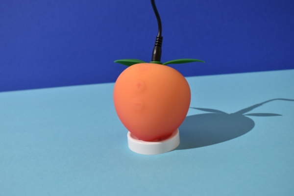 Womanizer Peach buttons connected to a charger