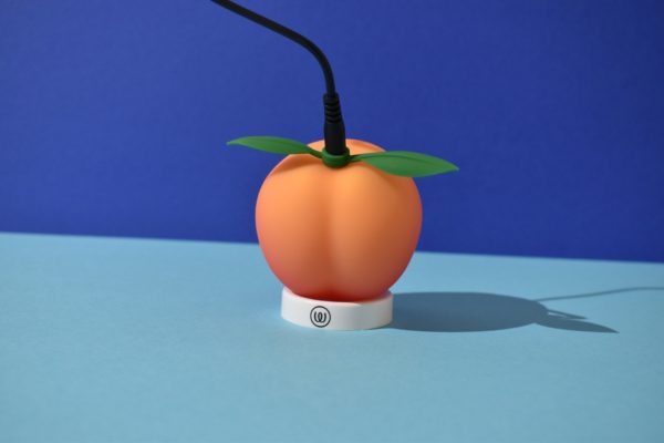Womanizer Peach connected to a charger