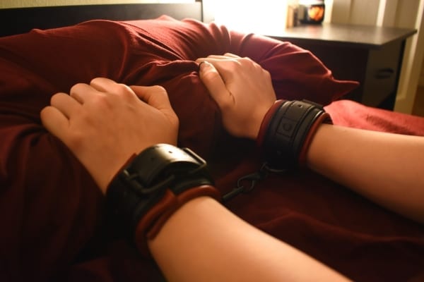 hands squeezing pillow wearing cuffs
